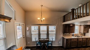 A modern kitchen with dark wood cabinets, a marble countertop, and a dining area with a table and chairs.