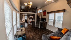 A compact living space with a dining area, kitchenette, and a staircase leading to an upper level.