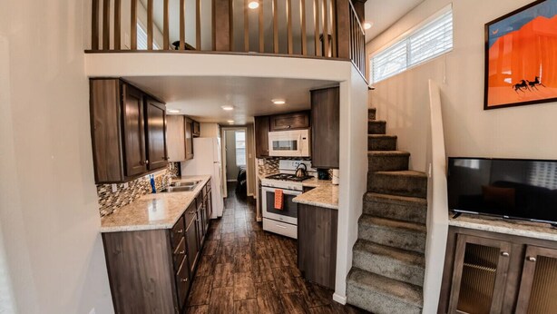 A modern kitchen with dark wood cabinets, a granite countertop, and a stainless steel range hood.