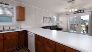 Cocina con armarios de madera, lavavajillas y encimera blanca.
