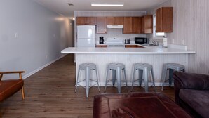 Una cocina moderna con armarios de madera, encimera blanca y una isla central con taburetes de bar.