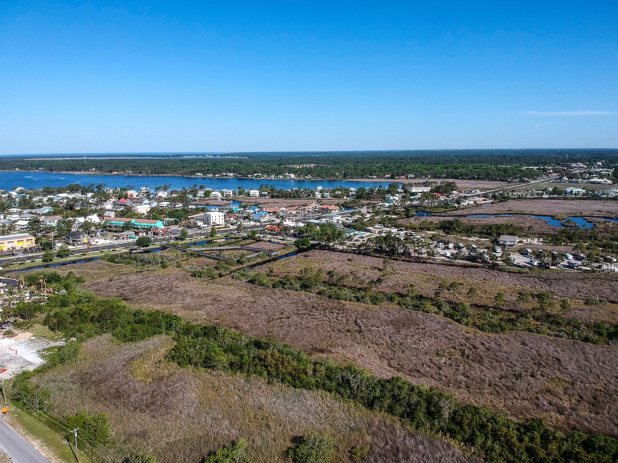 An aerial view of a coastal town with residential areas, a marina, and a large body of water.