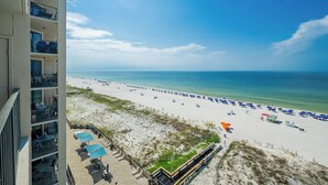 A beach view from a balcony with a clear sky, white sand, and blue water. - Phoenix X 809 - Lovely 3BR Gulf Front Unit (Orange Beach)