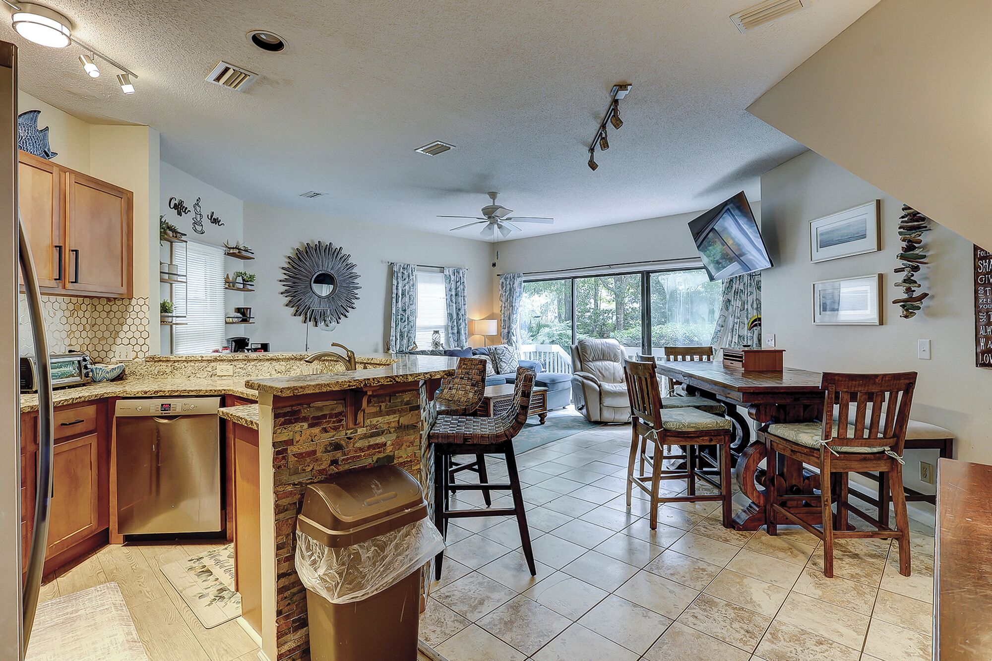 A spacious kitchen with a dining area, a ceiling fan, and a large window providing natural light.