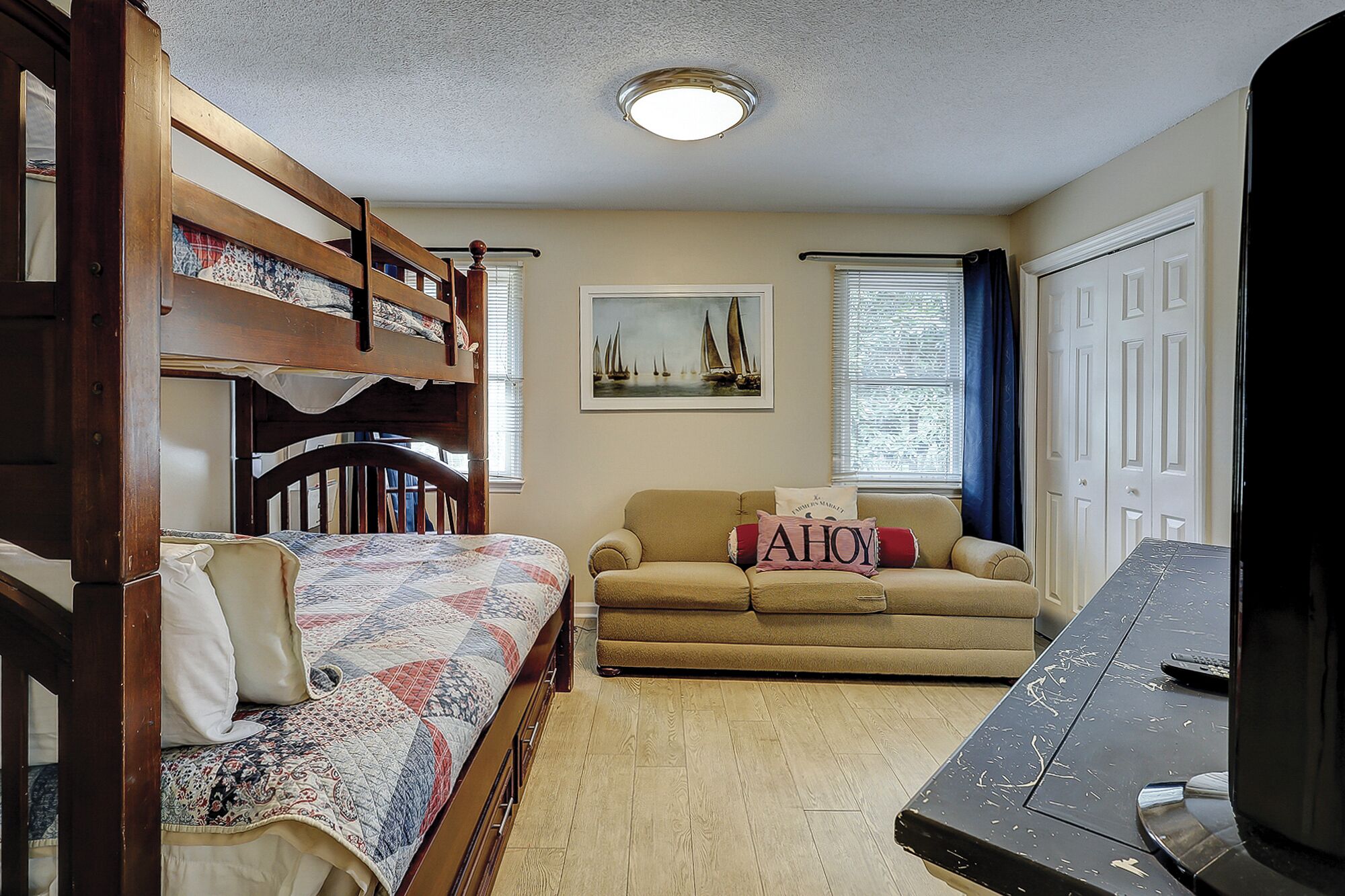 Une chambre avec un lit superposé, un canapé, une télévision et un tableau accroché au mur.