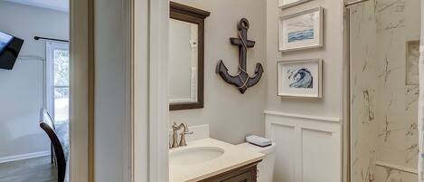 A bathroom with a double sink vanity, a toilet, a shower, and framed artwork on the walls.
