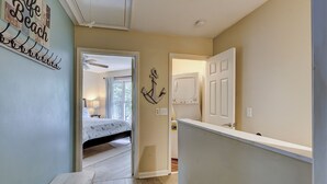 Un pasillo con una cama, un lavadero y una puerta que da a otra habitación.