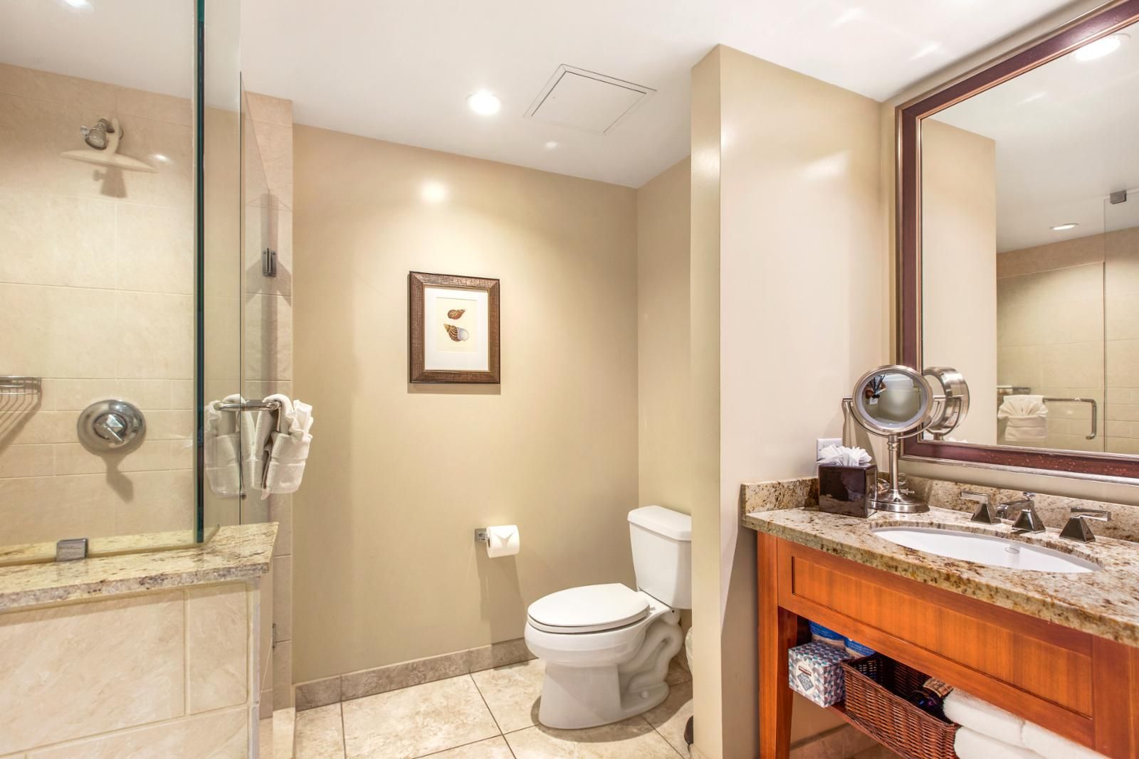 A modern bathroom with a glass-enclosed shower, a toilet, and a vanity with a mirror.