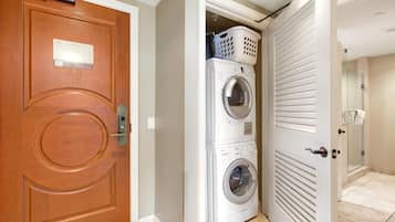 A laundry room with stacked washers and dryers, a wooden door, and a glass shower door.