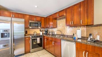 A modern kitchen with wooden cabinets, stainless steel appliances, a tiled backsplash, and a granite countertop.