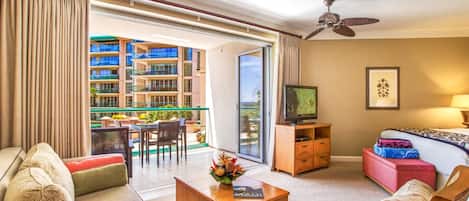 Habitació d'hotel amb un balcó, televisió, sofà, taula de cafè i llit.