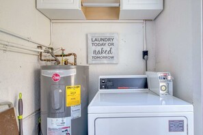 A laundry area with a Rheem water heater, a Speed Queen dryer, and a sign that reads 'LAUNDRY TODAY OR naked TOMORROW.'