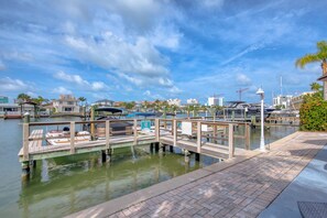A marina with docked boats, a wooden pier, and a cityscape in the background.
