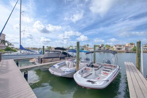 A marina with two boats docked, a wooden dock, and a clear sky.