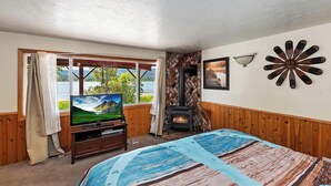 A cozy room with a bed, a television, a fireplace, and a window with a view of a lake.