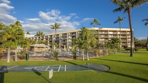 A hotel with multiple balconies, a swimming pool, and palm trees. - Oceanfront Bliss • Ground Floor • Steps to Beach & Pool (Kihei)