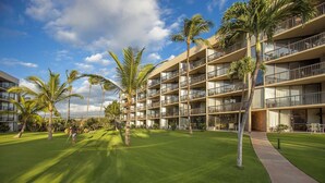 A multi-story hotel with a well-maintained lawn and palm trees. - Oceanfront Bliss • Ground Floor • Steps to Beach & Pool (Kihei)