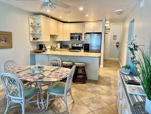 A kitchen with white cabinets, a microwave, a refrigerator, and a dining area with a table and chairs.