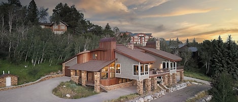 A modern multi-story house with a stone facade, large windows, and a curved driveway.