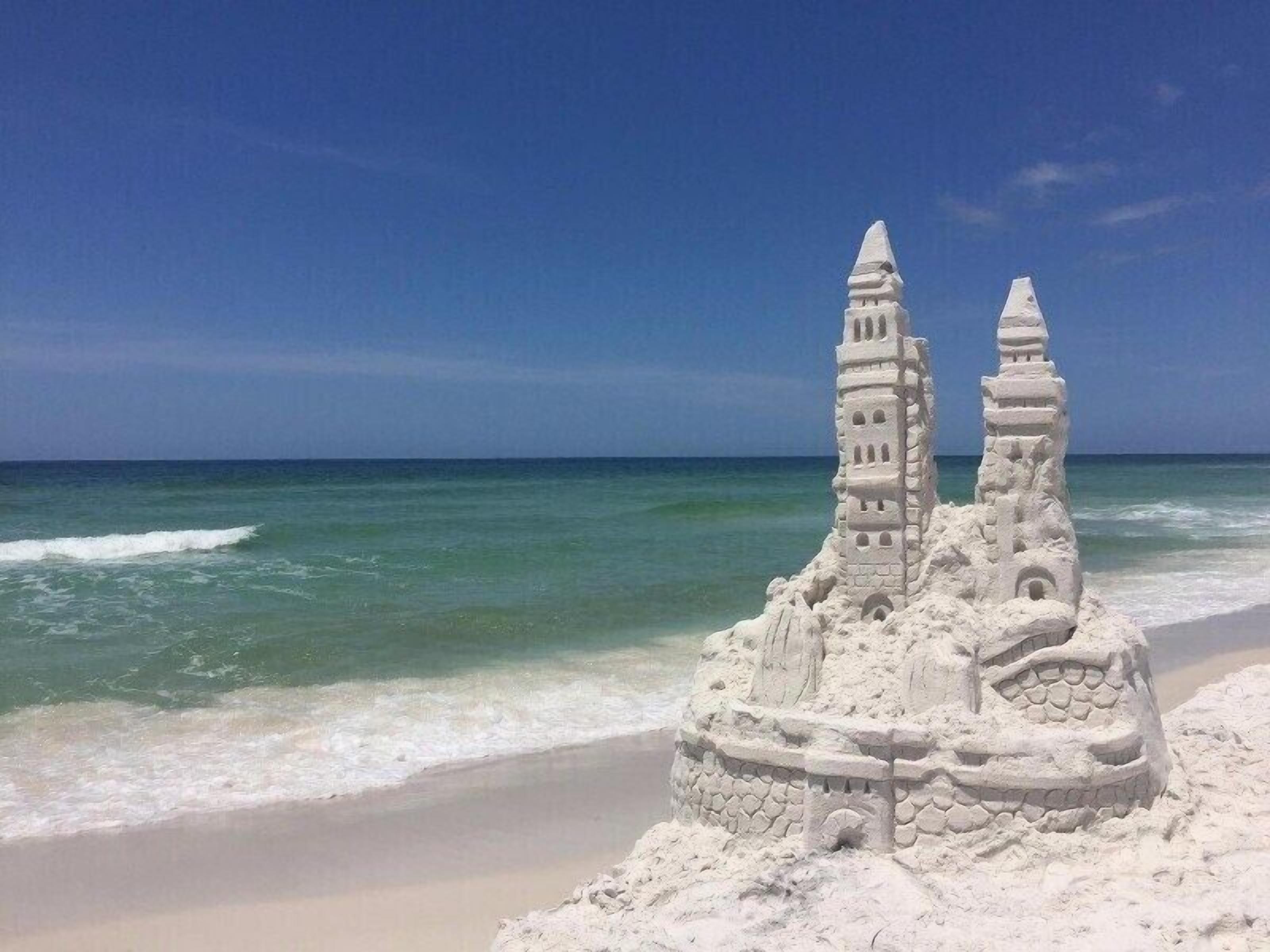 Ein Sandburg mit zwei Türmen am Strand.
