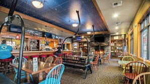 A cozy bar area with wooden tables and chairs, a bar counter, and a fireplace. - Modern 3-bedroom Seventh Mountain Resort Condo (Bend)
