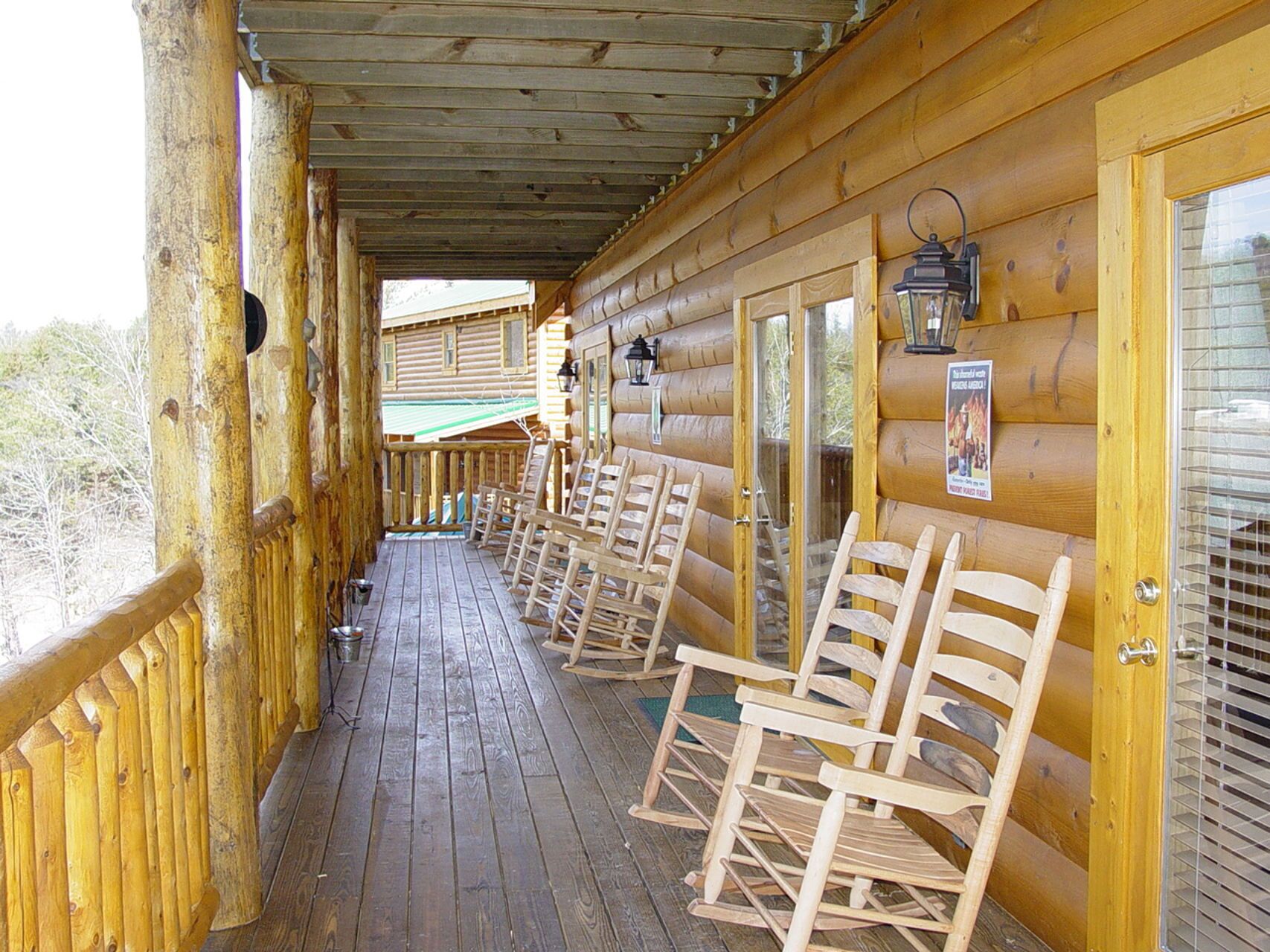 Une cabane en bois dotée d’un porche couvert, de fauteuils à bascule et d’une porte vitrée donnant sur une terrasse.