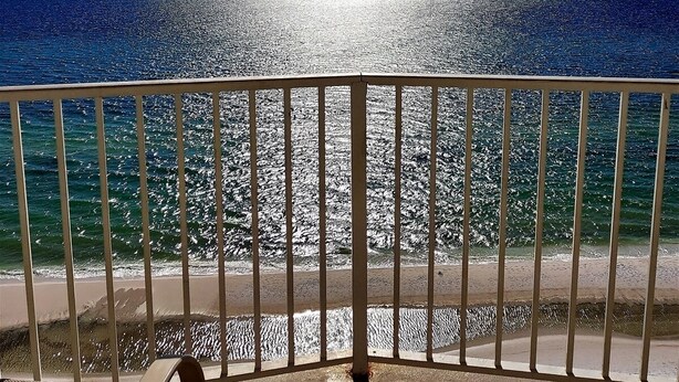 A balcony with a view of the ocean and a clear sky.
