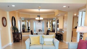 A spacious living room with a light blue sofa, a dark brown coffee table, and a red throw pillow.