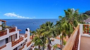 A coastal hotel with balconies overlooking the sea, palm trees, and a clear blue sky. - H1782: Spacious & Bright Villa with Ocean Views, Golf Cart, 2 Fireplaces (Avalon)