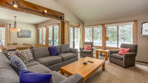 Amplia sala de estar con un sofá grande, dos sillones, una mesa de centro de madera y una zona de comedor al fondo.
