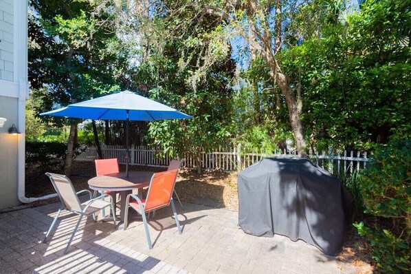 An outdoor patio with a table and chairs, a blue umbrella, and a barbecue grill. - 2 Roadrunner, 6 Bdrm, Private Pool/Spa, Ocean Peaks, Overlooks Sonesta Resort (Hilton Head Island)