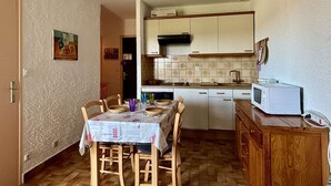 A compact kitchen with a dining table, chairs, a microwave, and a cabinet.