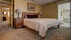 A bedroom with a large bed, two bedside tables, a ceiling fan, and a door leading to a balcony.