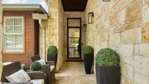 A stone-walled corridor with wicker furniture and planters. - PRIVATE LUXURY HOME!!!  4mi to Downtown |4 Bedrm | 3 Bath | Sleeps 8 (Austin)