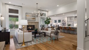 A spacious living room with a fireplace, a dining area with bar stools, and a kitchen with modern appliances. - PRIVATE LUXURY HOME!!!  4mi to Downtown |4 Bedrm | 3 Bath | Sleeps 8 (Austin)
