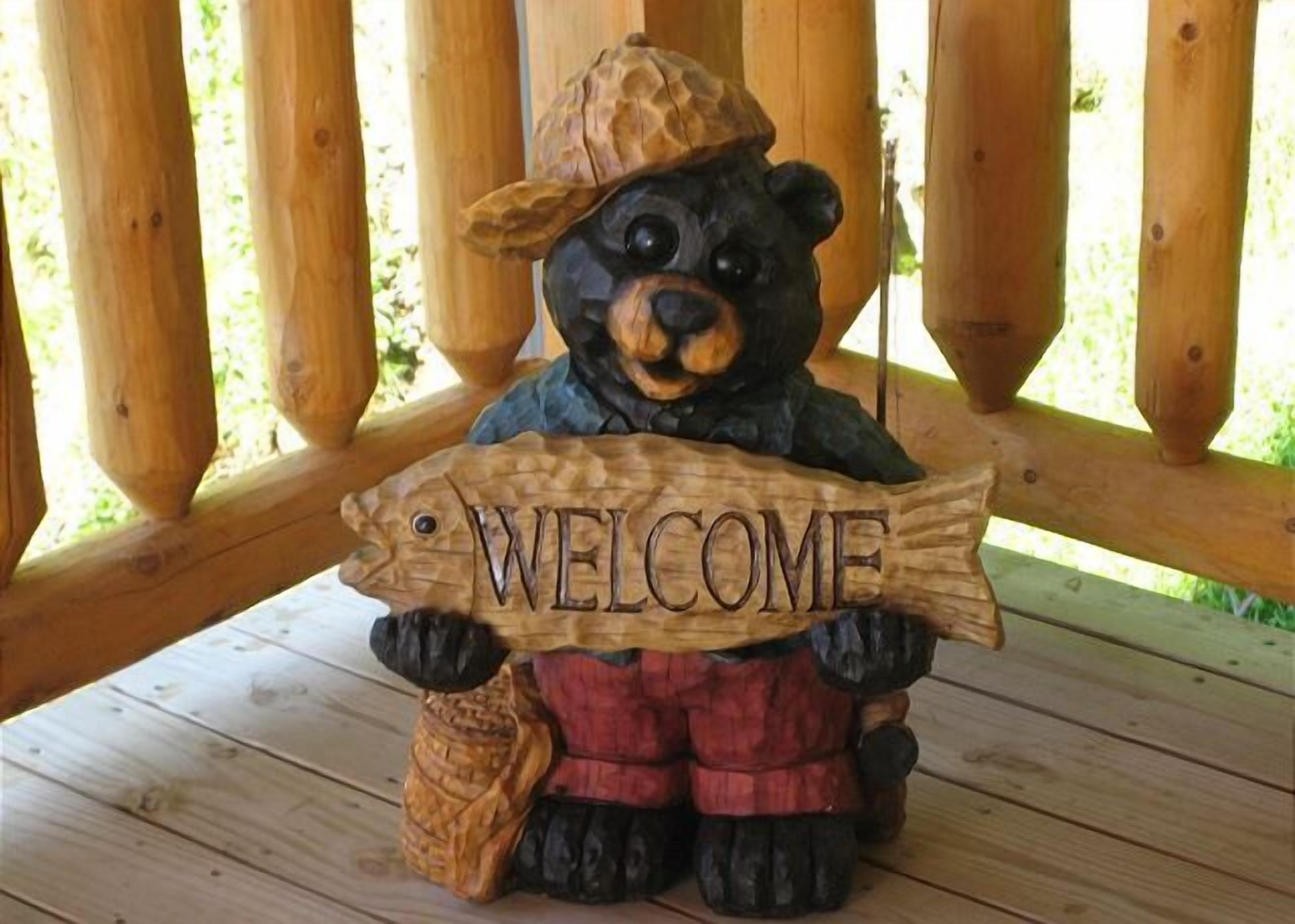Uma figura de um urso de madeira segurando uma placa com a palavra 'WELCOME'.