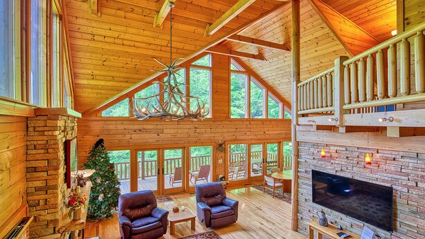 Un intérieur spacieux en bois, agrémenté d’une cheminée, de fauteuils en cuir et d’un sapin de Noël.