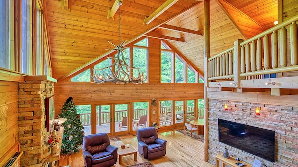 Cozy cabin interior with a fireplace, comfortable seating, and a flat-screen TV.