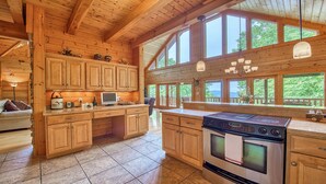 Une cuisine spacieuse avec des meubles en bois, une grande cuisinière et un coin repas offrant une vue sur l’extérieur.