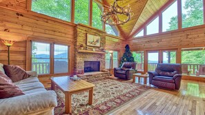 Cozy cabin with a fireplace, comfortable seating, and a decorative tree, perfect for a relaxing getaway.