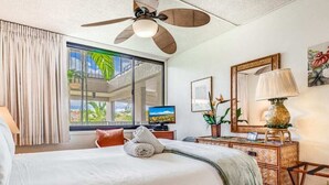 Una habitación de hotel con cama, escritorio, lámpara y ventilador de techo.