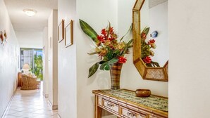Un pasillo con una consola de madera, un jarrón de flores y un espejo.