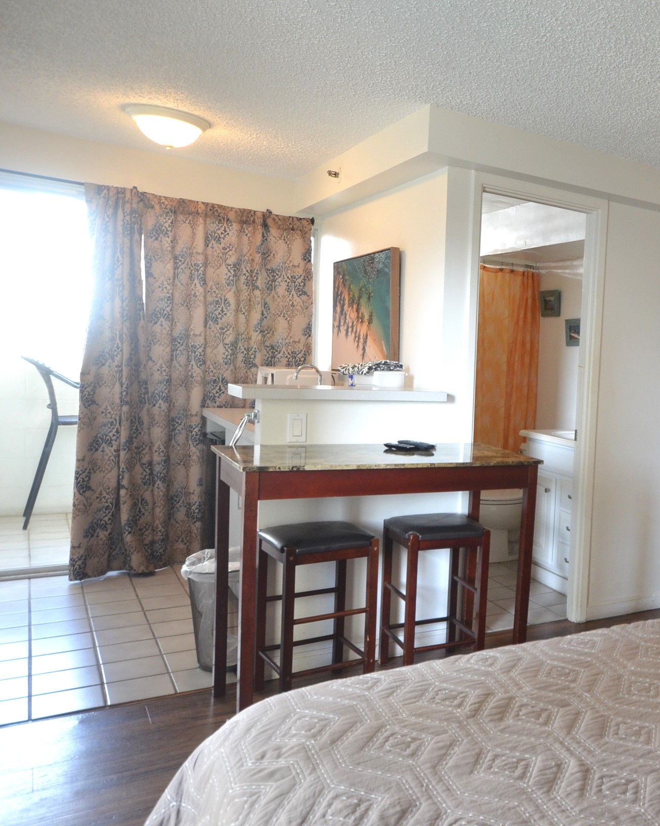 Habitación de hotel con cama, una kitchenette pequeña, baño y vistas al exterior.
