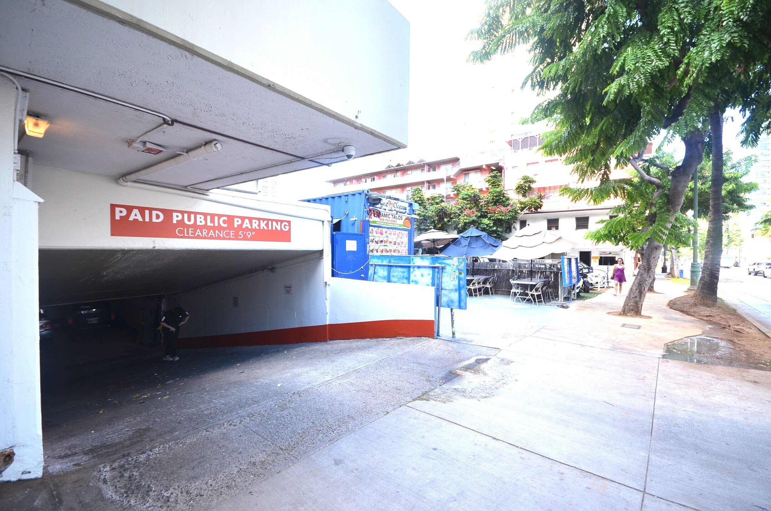 A parking garage entrance with a sign indicating paid public parking and a clearance height of 5 feet.
