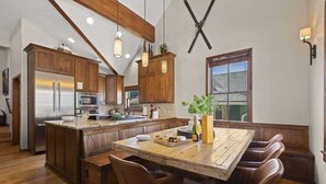 A kitchen with wooden cabinets, a central island with seating, and a large window.