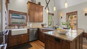 A kitchen with wooden cabinets, a large island, a sink, and pendant lights.