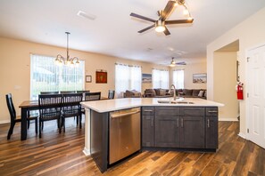 Una cocina amplia con una isla central, muebles oscuros y un comedor con mesa y sillas de madera.