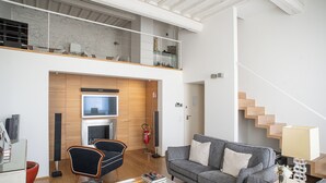 Een moderne woonkamer met een grijze bank, een glazen salontafel en een open haard.