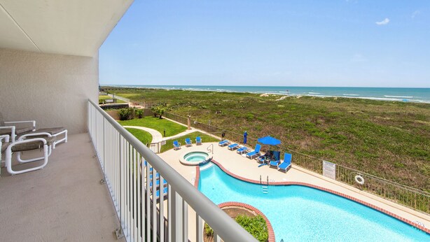 A balcony with a view of a beach and a swimming pool with lounge chairs. - Edgewater 304 Sandy Beach and a heated swimming pool. (South Padre Island)