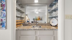 A kitchen with a granite countertop, white cabinets, a stainless steel sink, and a ceiling fan. - Edgewater 304 Sandy Beach and a heated swimming pool. (South Padre Island)